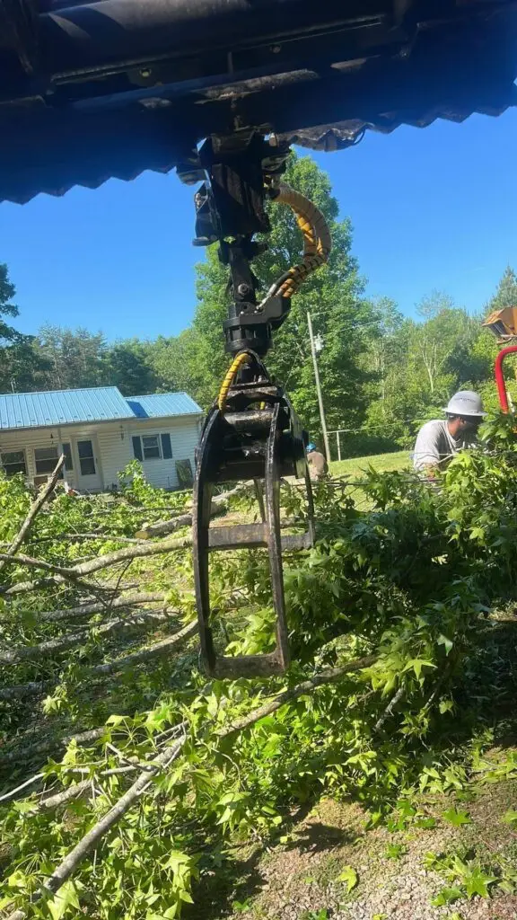 Grapple lifting a trunk section over a house
