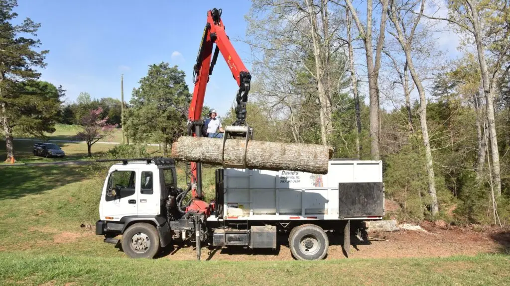 Grapple truck lifting a log on a residential job